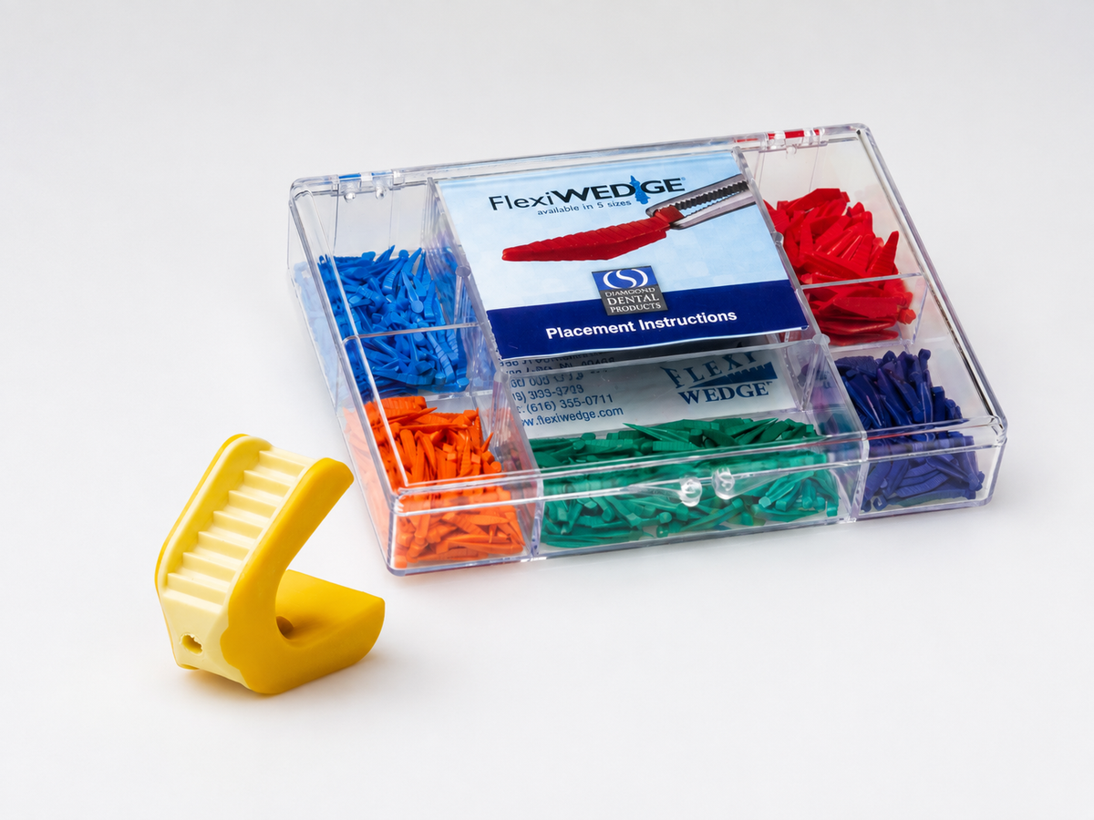 A clear plastic organizer tray containing multiple wedge-shaped finger cushions in blue, red, orange, green, and dark blue, with a yellow wedge piece placed in front on a white studio background. The tray label reads FlexiWEDGE and Placement Instructions.